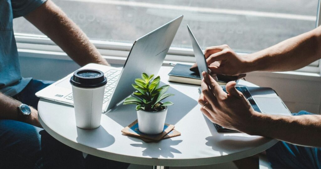 カフェ風のテーブルでパソコンを開き、仕組みづくりの打ち合わせをする様子。LincUpの伴走支援を象徴するイメージ